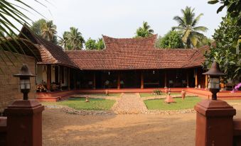 a traditional indian house with a red roof and a large courtyard surrounded by palm trees at Emerald Isle