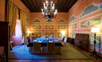 a room with a large dining table surrounded by chairs , and a piano in the background at Parador de Jarandilla