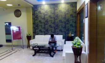 a man sitting on a couch in a room with green and white patterned wallpaper at Hotel International