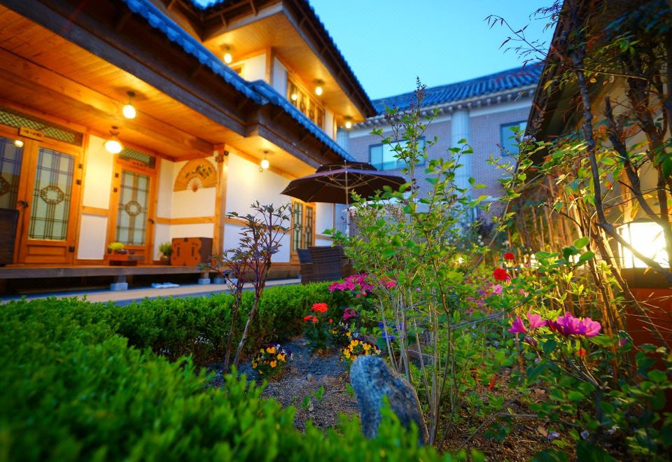 There is a garden with flowers and plants at the entrance of an oriental-style building at Jeonju Dwaejikkum Hanok