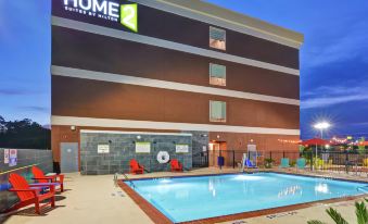 a large hotel with a swimming pool and outdoor seating area , lit up at night at Home2 Suites by Hilton la Porte