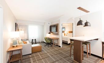 a modern hotel room with a living area , dining table , and kitchenette , all furnished with comfortable furniture at Staybridge Suites Denver North - Thornton