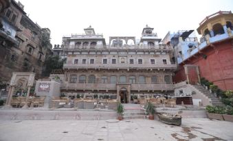 a large , ornate building with multiple levels and balconies , surrounded by a courtyard filled with potted plants at Guleria Kothi at Ganges