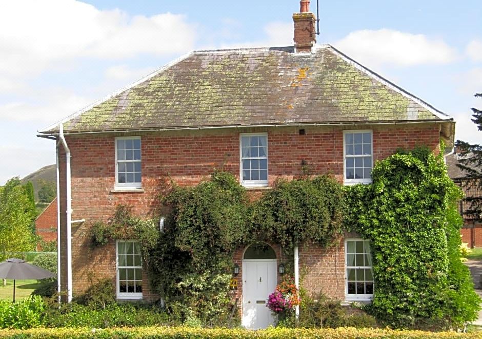 a brick house surrounded by greenery , with a white door and window arrangement in the foreground at Home Farm Boreham