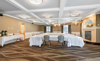 a large , empty conference room with white tables and chairs , surrounded by wooden paneling and ceiling lights at Best Western Plus Executive Court Inn  Conference Center