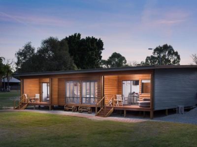 a modern , wooden - framed house with large windows and a balcony , situated in a grassy field at The Swan Valley Retreat