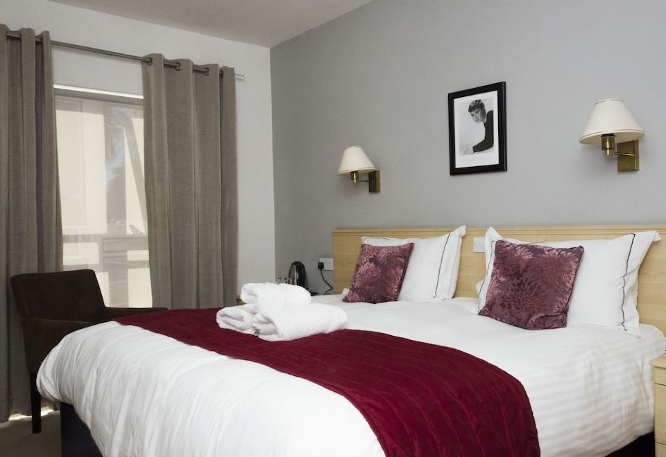 a large bed with a white and red blanket is in a room with a window at Beachcombers Hotel