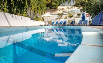 a large , blue swimming pool surrounded by white lounge chairs and umbrellas , with a white building in the background at Amazona