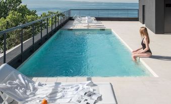 a woman sitting on a lounge chair near a pool , overlooking the ocean while enjoying the view at Briig Boutique Hotel