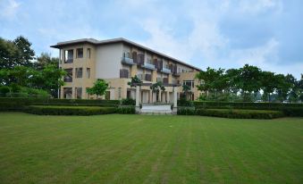 a large , modern building with multiple balconies and windows , surrounded by lush green grass and trees at Ritz Resort