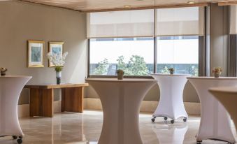a modern office space with white tables and chairs , large windows , and a vase of flowers at Hesperia Barcelona Sant Just