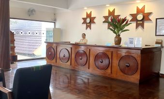 a receptionist sitting at a desk in a room with wooden floors , surrounded by chairs at DAM San Hotel