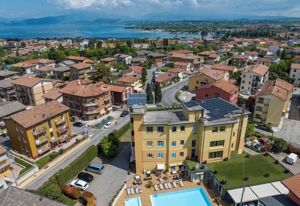 aerial view of a small town with a swimming pool surrounded by buildings , trees , and a body of water in the background at Green Park Hotel