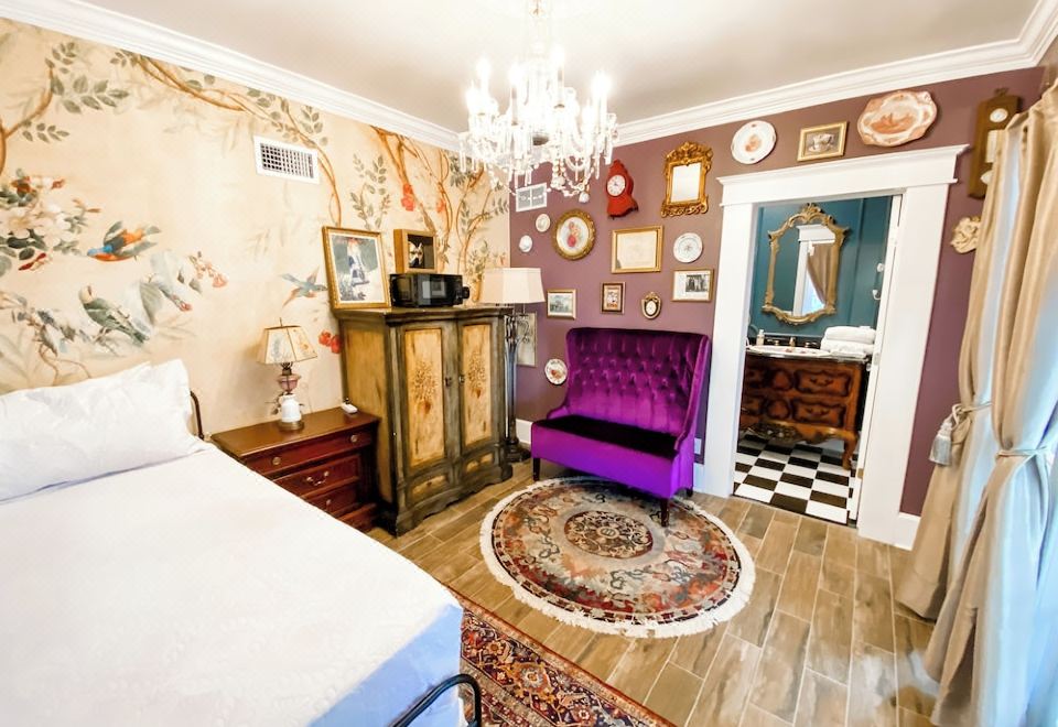 a room with a purple bed , purple chair , and a chandelier hanging from the ceiling at Park Place Inn and Cottages