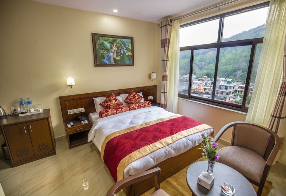 a bedroom with a large bed , red and gold comforter , and a view of the city through a window at Hotel Avenue