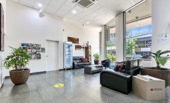 a large , open - concept living room with multiple couches and chairs arranged around a coffee table at Argus Hotel Darwin