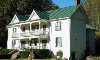 a large white house with a green roof and multiple windows , situated in a grassy field at The Mountain Rose Inn