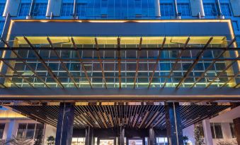 a modern building with a glass facade and a wooden ceiling , featuring potted plants and a covered walkway at Ames Hotel