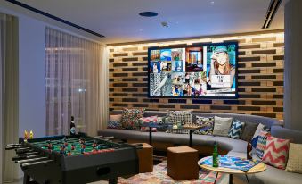 a cozy living room with a pool table , foosball table , and a flat - screen tv mounted on the wall at Moxy Patra Marina