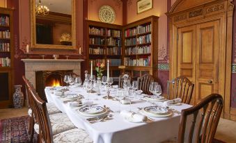 a formal dining room with a long table set for a meal , surrounded by chairs and a fireplace at Pale Hall Hotel