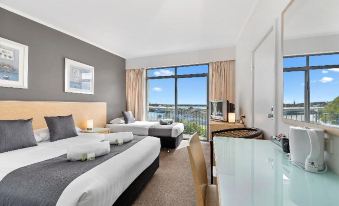 a modern hotel room with two beds , a tv , and a view of the ocean at Scamander Beach Resort