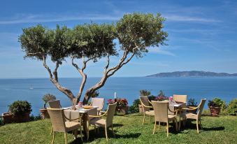 a dining table set up for a meal on a patio overlooking a body of water at Boutique Hotel Torre di Cala Piccola
