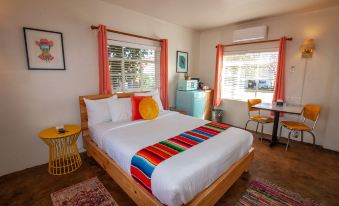 a bedroom with a large bed , a refrigerator , and a tv . the room has a colorful blanket on the bed at Antelope Lodge