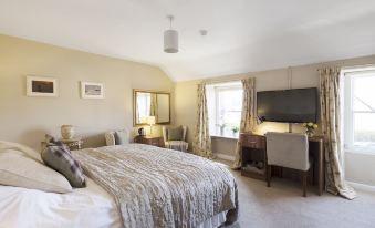 a large bedroom with a king - sized bed , a tv mounted on the wall , and a window at Allanton Inn