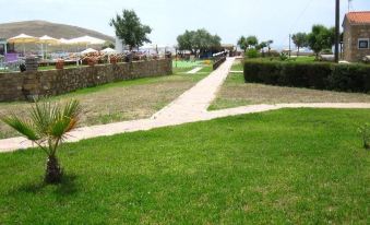 a grassy area with a stone wall and bushes , as well as a stone path leading to the ground at Villa Victoria