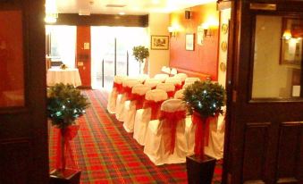 a room set up for a wedding or other formal event , with chairs arranged in rows and decorated with christmas trees at The Bridge Inn