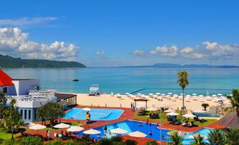 a sunny day at a resort with a beach , pool , and ocean view , under a clear blue sky at Okuma Private Beach & Resort