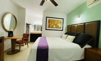 a hotel room with a king - sized bed , a desk , and a bathroom next to it at Cactus Inn Los Cabos
