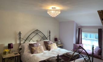 a luxurious bedroom with a large bed , two nightstands , and a chandelier hanging from the ceiling at Evangelisa