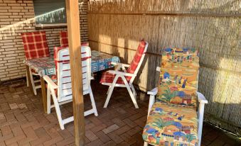 a patio area with a table , chairs , and a colorful chair under a wooden fence at Christine