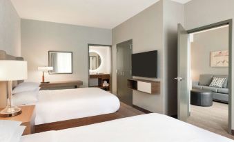 a hotel room with two beds , a flat - screen tv mounted on the wall , and a bathroom at Embassy Suites by Hilton South Jordan Salt Lake City