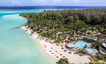 aerial view of a tropical beach resort with a large pool surrounded by palm trees at Le Bora Bora by Pearl Resorts