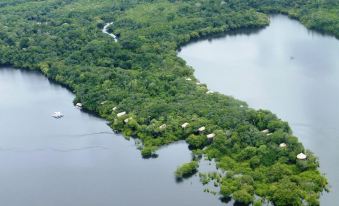 a lush green forest with a large body of water , surrounded by small wooden structures at Juma Amazon Lodge