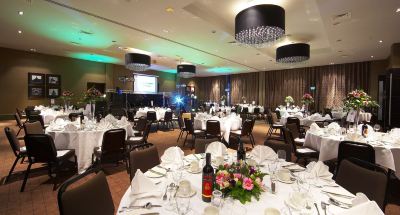 a well - decorated banquet hall with multiple tables set for a formal event , featuring white tablecloths , wine glasses , and decorative center at Village Hotel Liverpool