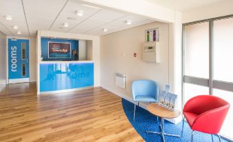 a modern office reception area with wooden flooring , blue furniture , and a blue couch , giving the impression of a modern office space at Travelodge Nottingham Trowell M1