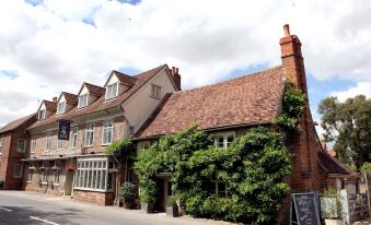 a brick building with ivy growing on it is located in front of a white building at The White Hart