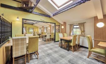 a spacious room with a wooden table and chairs , large windows , and a skylight , providing a bright and inviting atmosphere at The Old Ginn House Inn
