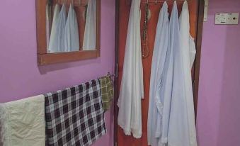 a room with clothes hanging on a rack and a plaid blanket hanging on the wall at Adamson Inn Penang
