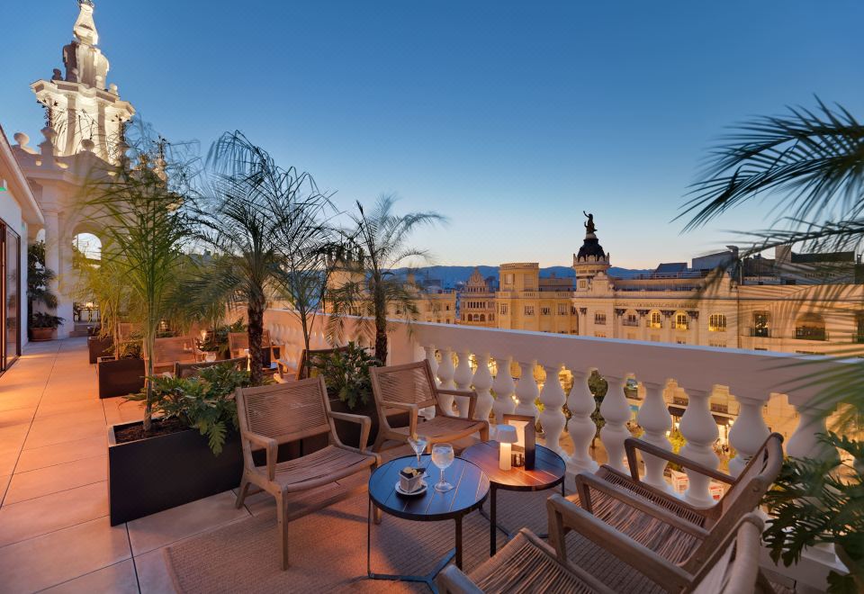 a rooftop patio with several chairs and a table set up for outdoor dining , overlooking a cityscape at H10 Palacio Colomera