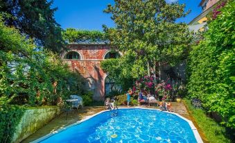 a group of people gathered around a swimming pool in a backyard , enjoying their time together at Hotel Villa Sermolli