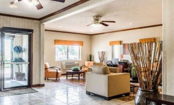 a spacious living room with high ceilings , tile floors , and wooden furniture , including a couch , chairs , and coffee table at Quality Inn Denver Northeast Brighton