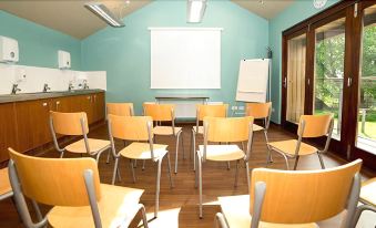 a classroom with rows of wooden chairs arranged in a semicircle , and a whiteboard on the wall at YHA Malham