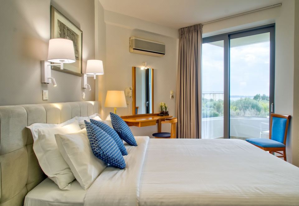 a well - decorated hotel room with a king - sized bed , blue pillows , and a view of the ocean at Poseidon Hotel