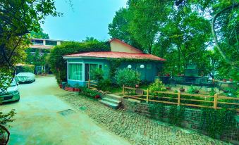 a brick house with a red roof is surrounded by trees and bushes , and a stone path leading up to it at Lockwood Hotel Murree