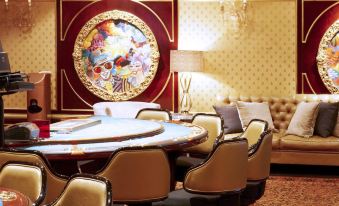 An ornate room is adorned with chairs, tables, and paintings on the walls at Carnival City Hotel