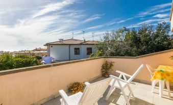 a balcony with white chairs and a blue sky , overlooking a building and trees in the background at Mansarda